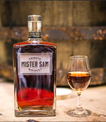 Mister Sam bottle in glencairn glass on floor with barrel in background