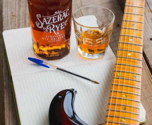 A bottle of Sazerac Rye and a glass beside a notebook